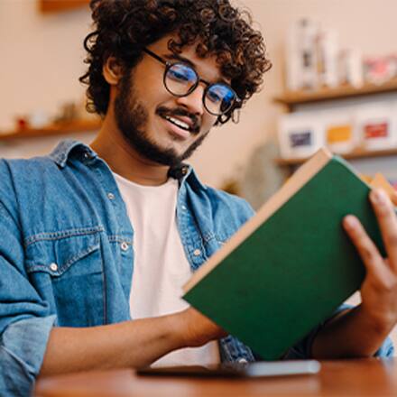 A man reading a book with a green cover.