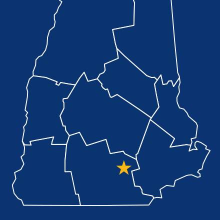 A blue map of New Hampshire with a yellow star denoting Manchester.