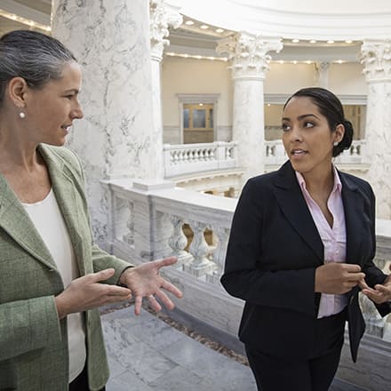 Two criminal justice professionals in conversation as they walk around courthouse hallways.