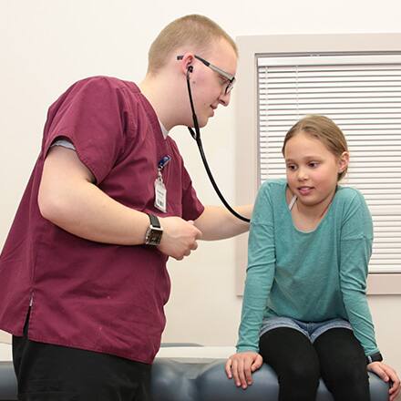 A clinical nurse leader using a stethescope on a pediatric patient.