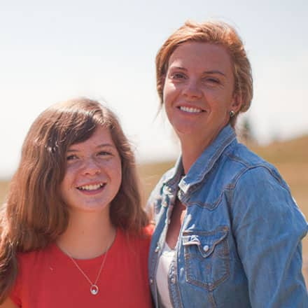 Tracey Burraston a 2015 BA in psychology graduate from SNHU and her daughter standing next to a brown horse