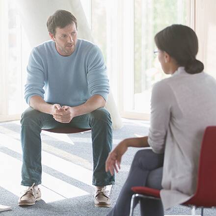 A psychologist and client sitting in chairs during a therapy session.