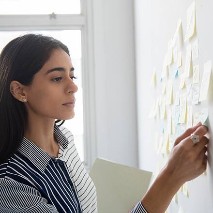 A woman reviewing her personal growth and professional development plan on sticky notes