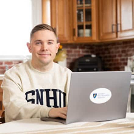 U.S. service member and SNHU graduate Rob Thomas doing online coursework on his laptop.