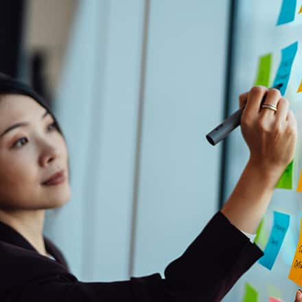 A woman writing down her short- and long-term goals for work on sticky notes