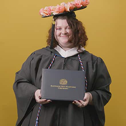 Shelbie Lynne Ayles, a 2025 graduate who earned her bachelor’s in psychology with a minor in sociology from SNHU wearing her cap and gown in front of a yellow background.