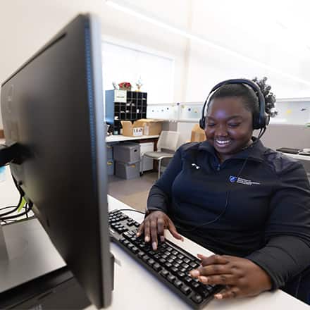A student support staff member at Southern New Hampshire University (SNHU) smiling while on a call with a student.