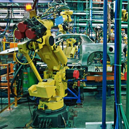 Large yellow robotics on an automobile assembly line where a manager with a technical degree might work.