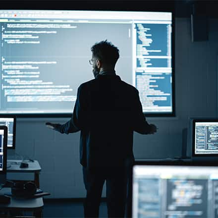 A person with a master's in computer science reviewing code on a big screen for his job