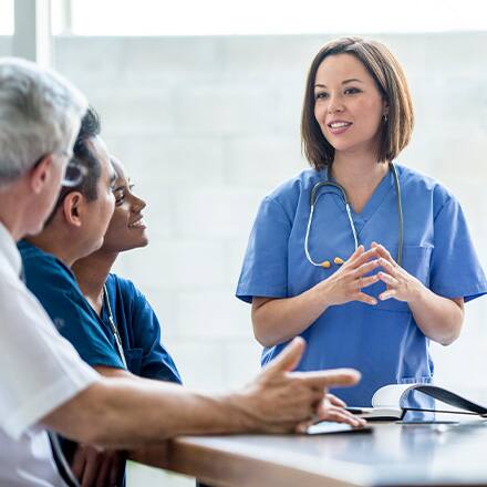 A medical professional with a stethoscope having a discussion with others in the medical field