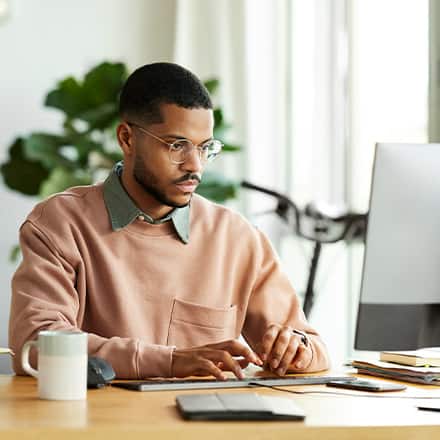 A man working on his desktop researching the types of graduate degrees