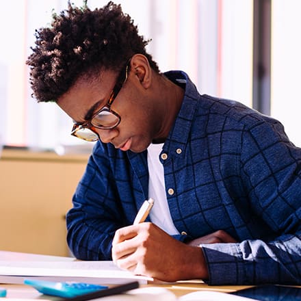 A man wearing glasses and a blue shirt studying for his associate degree.