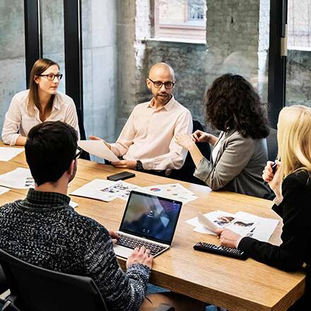 A group of men and women sitting around a conference room table working in their role as digital marketers.