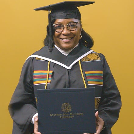 Valerie Craig, a 2025 graduate from SNHU with an associate degree in liberal arts, dressed in a cap and gown and holding her diploma.