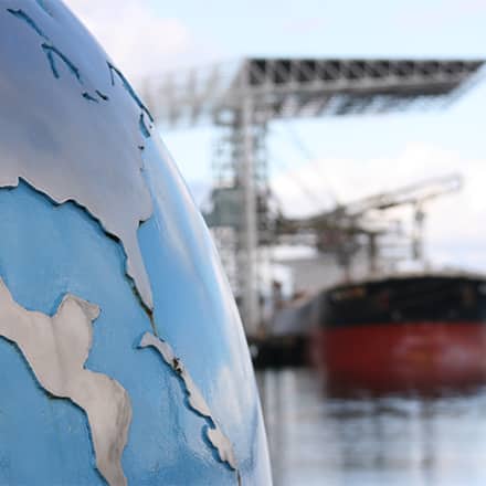 A globe statue by a seaport.