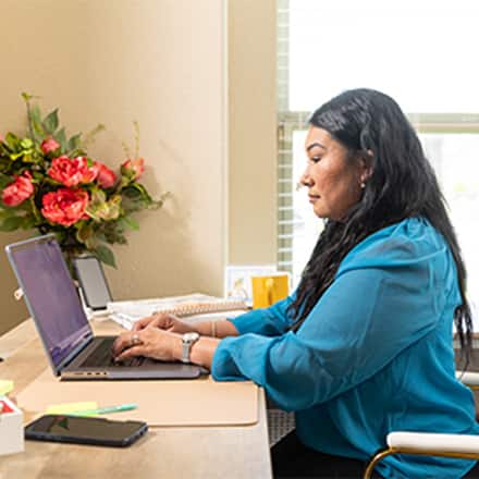 An adult college student researching at her laptop, to represent finding a transfer-friendly college.