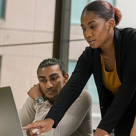 Two professionals with business degrees reviewing information on a laptop.