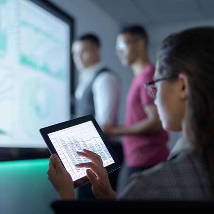 A woman with dark hair and glasses looking at data about what you can do with a finance degree on a tablet.