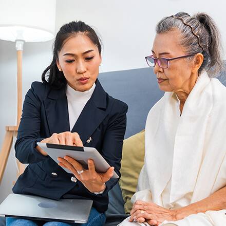A woman sitting with a caseworker looking at an iPad.