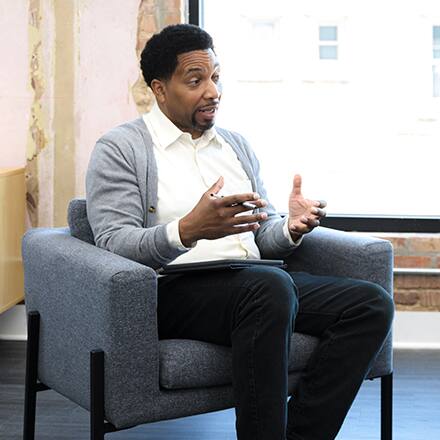 A seated counselor using his hands to help him explain a thought.