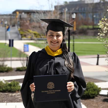 Maisoon Mir dressed in a graduation cap and gown, at SNHU, an institutionally accredited university, celebrating her Master of Science in Information Technology.