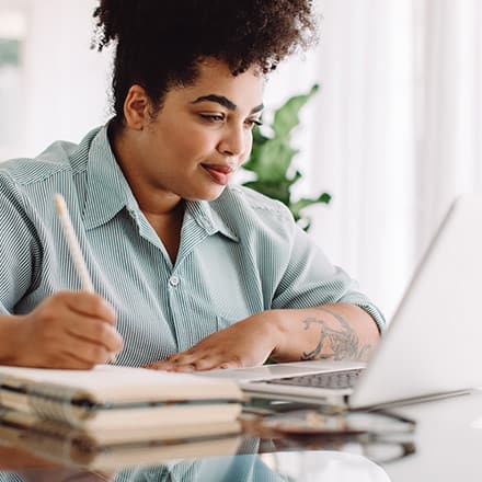 An MA student sitting at a desk taking notes off a laptop