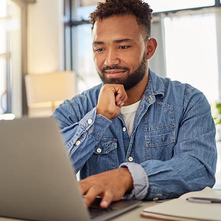 A recent college graduate on a laptop who is reading a cover letter he wrote for his resume.