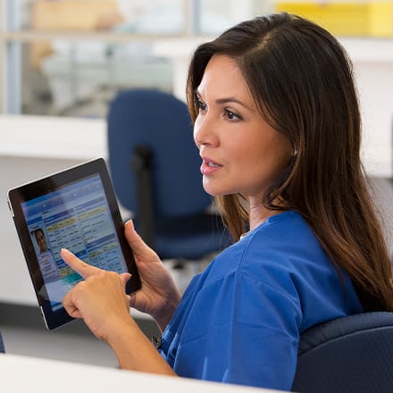 A health information management (HIM) professional using a tablet to access a patient's record