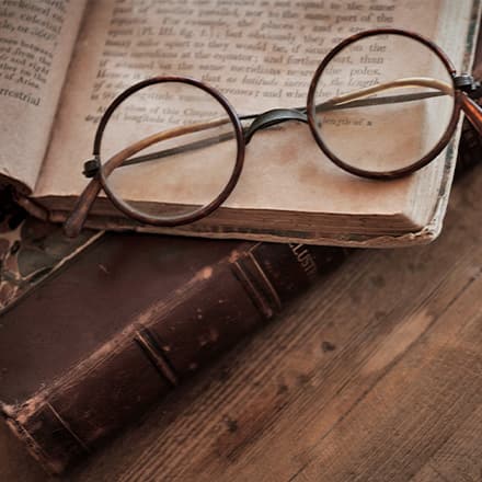 A pair of wire-rim glasses on top of an open book.