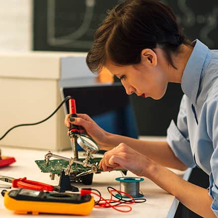 A female electrical engineer using a soldering tool to build an electronic component.