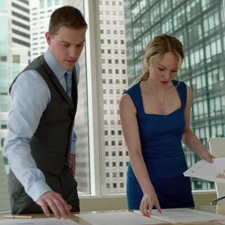 A man and a woman with master's degrees studying documents inside an office building.