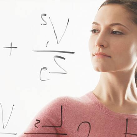 A person who knows why math is important, writing equations on a clear dry erase board.