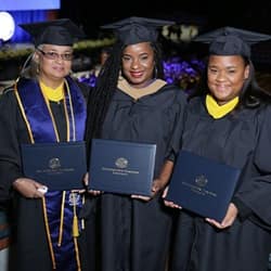 Mother Sabrina Mentis, left, with daughters Kellyann Alves, center, and Stephanie Mentis, right, all dressed in their SNHU graduation caps and gowns.