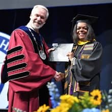 Dr. Paul LeBlanc, left, presenting DeMeeta Hulett, right, with a degree at SNHU Commencement