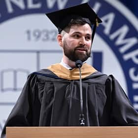 Alexander Anthony Angellakis, a student speaker at SNHU's 2025 Fall Commencement, at a podium, wearing a cap and gown.