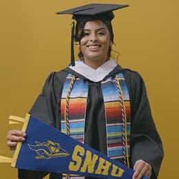 Angel Delatorre, BA in Psychology graduate from SNHU and U.S. Army veteran, holding SNHU flag.