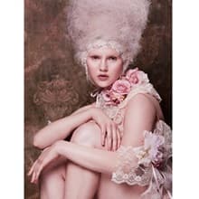The photography category's winning submission, 'Pastel Beauty.' A woman wearing pink flowers and a tall wig with her knees drawn to her chest.