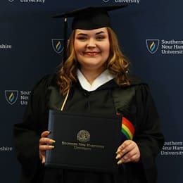 Ashley Smith, a 2024 SNHU graduate who earned her bachelor's in communication wearing her cap and gown in front of a dark blue background.