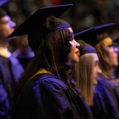 Brendaliz De Los Santos in a crowd at her Commencement ceremony, dressed in a graduation cap and gown.