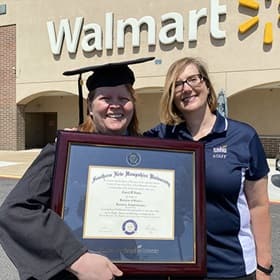 Carol D'Anna and Michele Albion holding Carol's diploma in front of Walmart
