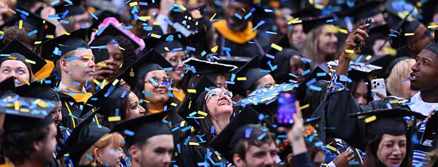 Spring 2026 SNHU Commencement students celebrating their graduation with confetti.
