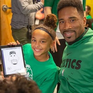 Former Celtics forward Leon Powe and a student who is showing off her work on a tablet