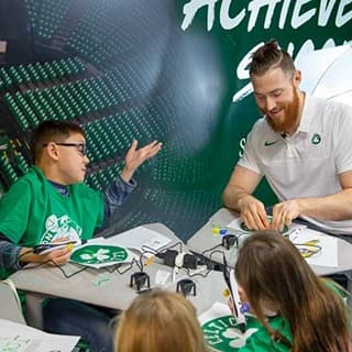 Celtics center Aron Baynes working with students at a table
