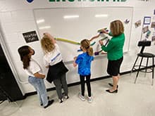 Children and a teacher doing STEAM Lab activity on a board