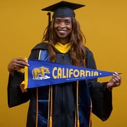 Chantel Hutchison, a 2025 SNHU graduate who earned her bachelor's in public health, holding wearing her cap and gown in front of a yellow background holding a California state flag.