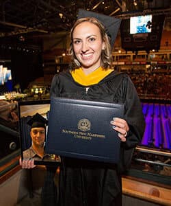 Alexandra White at SNHU's 2018 commencement holding an ipad with a photo of her husband and fellow graduate Tyler White.