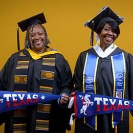 Debra Douglas and Deidra Fransaw holding Texas state flags in front of a yellow background at their SNHU commencement ceremony.