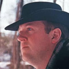 Derrick Craigie, a senior associate dean of liberal arts at SNHU, wearing a black hat, wearing a scarf and coat outdoors.