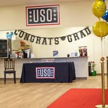 A surprise graduation celebration with a congrats grad sign with yellow and blue balloons