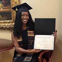 Donnica Coleman wearing a graduation cap and holding a certificate of achievement at MCB Quantico graduation ceremony.